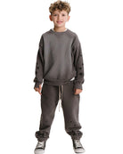 A young boy modeling a dark gray crewneck sweatshirt and matching jogger pants with black star details, paired with black and white sneakers, against a plain white background.