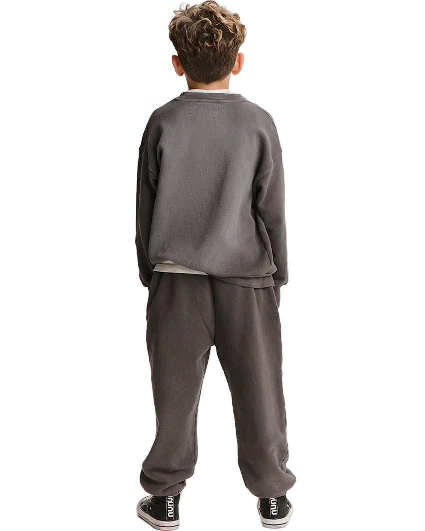 A child viewed from the back wearing a dark gray sweatshirt and matching sweatpants, with black sneakers, against a plain white background.
