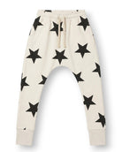 Off-white jogger pants for kids with an all-over black star print, featuring an elastic waistband with a drawstring and ribbed ankle cuffs, shown against a plain white background.